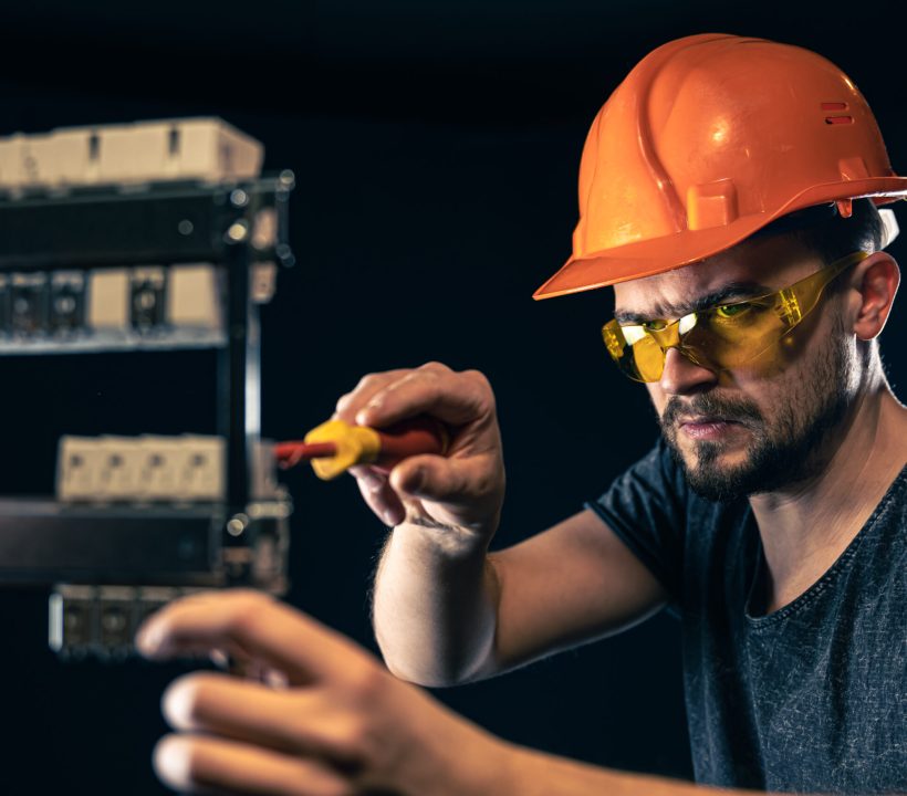 male electrician works switchboard with electrical connecting cable scaled